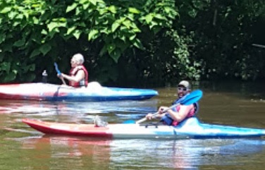 Family kayaking on the river by the pavilion